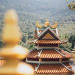 Beautiful temple architecture nestled in a lush, mountainous setting on a sunny day.